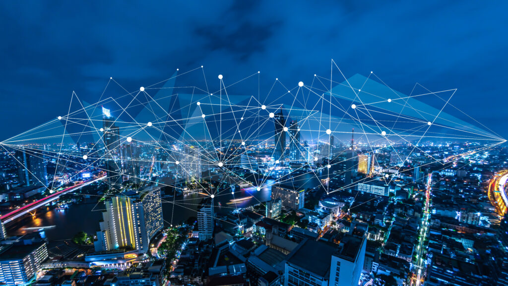 Aerial view of a city at night with glowing network lines connecting various points.